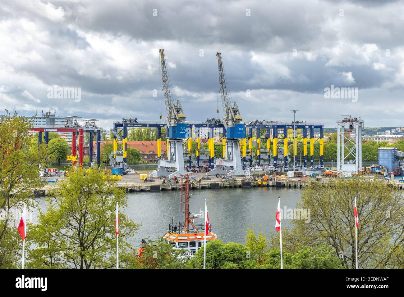 Danzica, Polonia - 4 maggio 2025: Il cantiere. Le gru portuali dominano il paesaggio urbano, evidenziando l'intersezione tra industria e natura sotto una nuvolosa Foto Stock