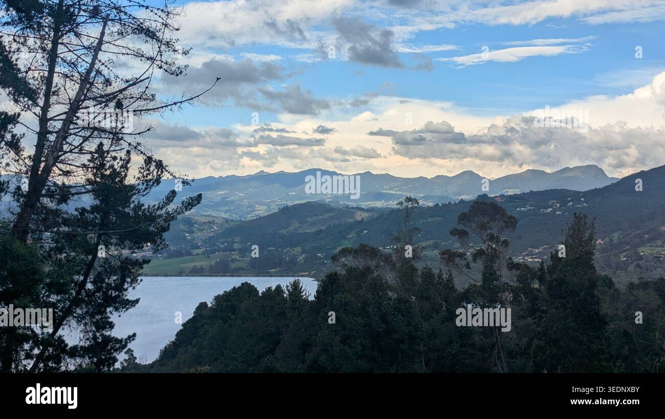 Vista panoramica di un tranquillo lago circondato da montagne e pini al crepuscolo. Paesaggio ad alta quota con luce naturale soffusa. - Immagine stock catturata con smartphone