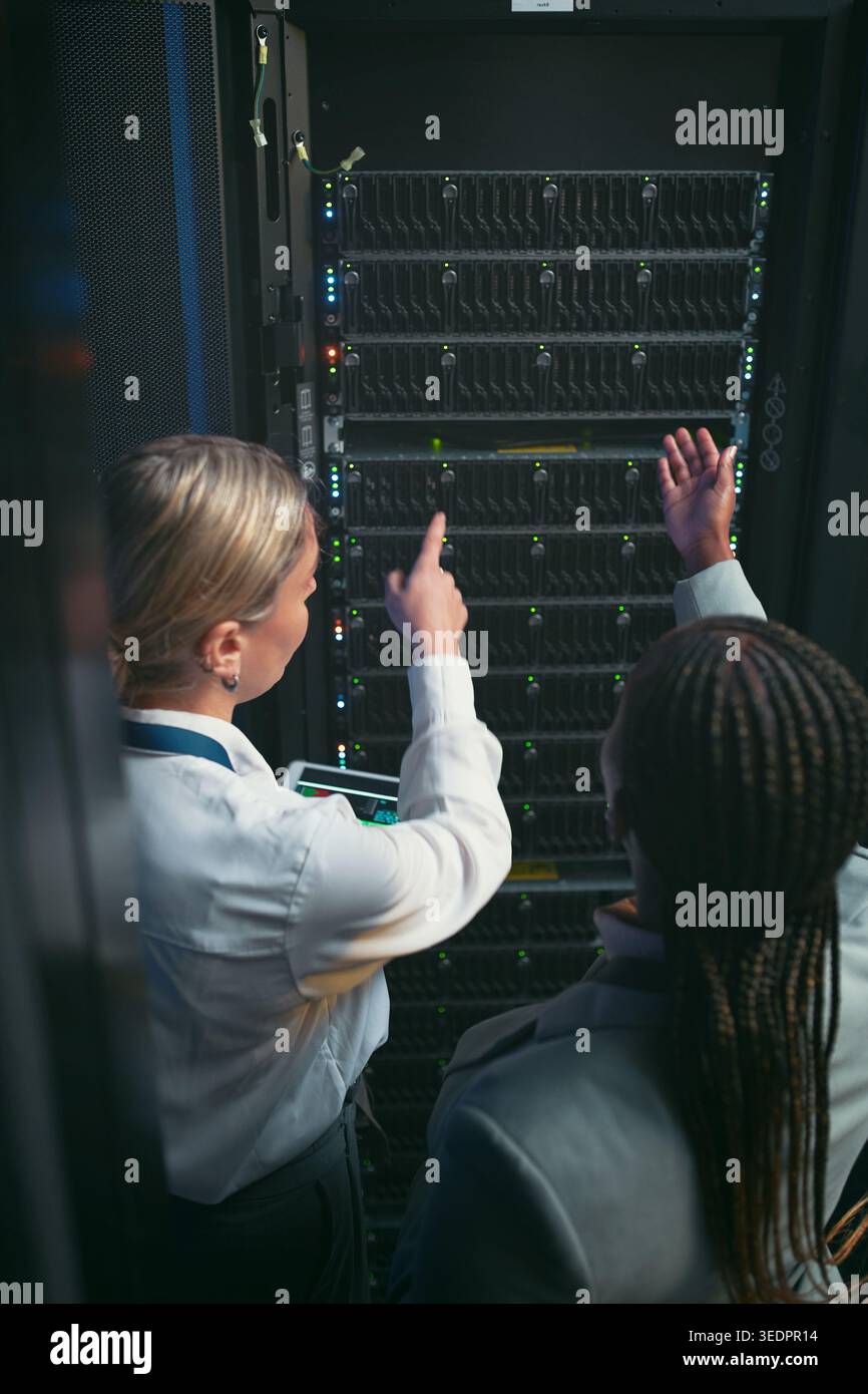 Tablet, donne e conversazioni in sala server per database, prestazioni di sistema o aggiornamento. Persone, back e ispezione nel data center per la rete Foto Stock