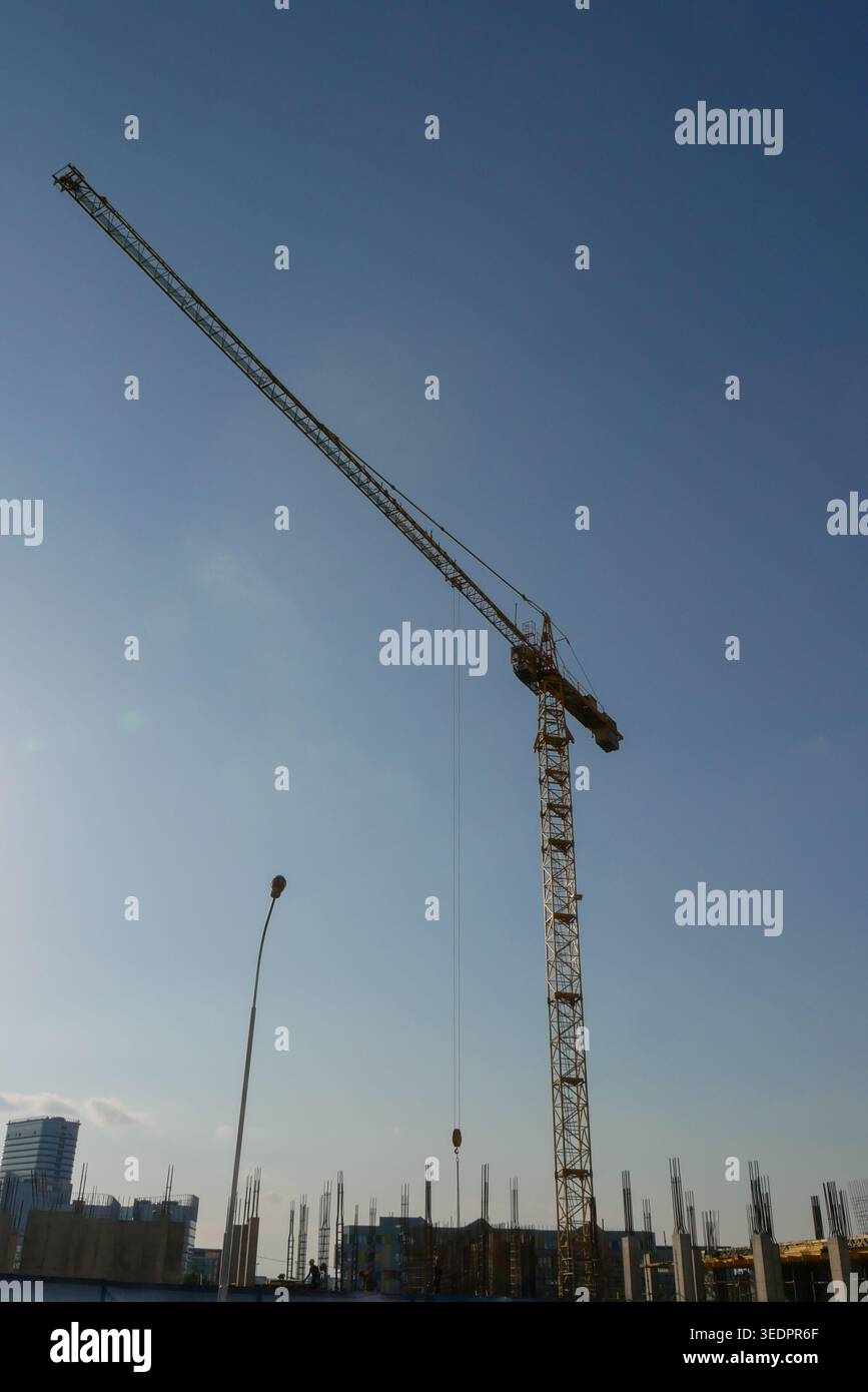 Il cielo azzurro incornicia i macchinari industriali. La luce del sole splende sulla struttura in acciaio. Gli edifici sorgono dietro un quadro scheletrico Foto Stock