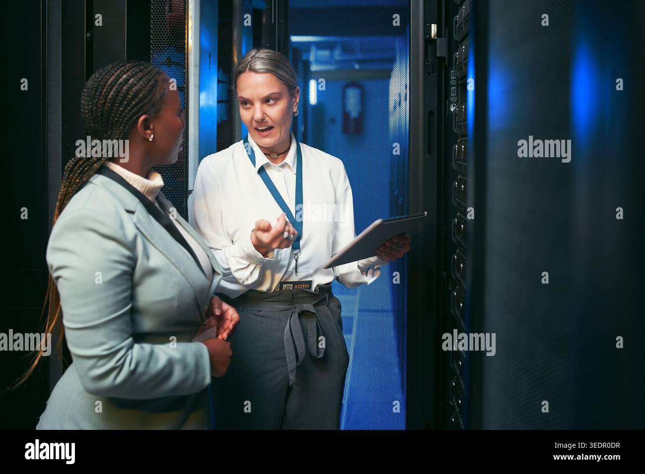 Tablet, donne e discussioni in sala server per database, prestazioni di sistema o aggiornamento. Personale, ispezione e tecnico nel data center per la rete Foto Stock
