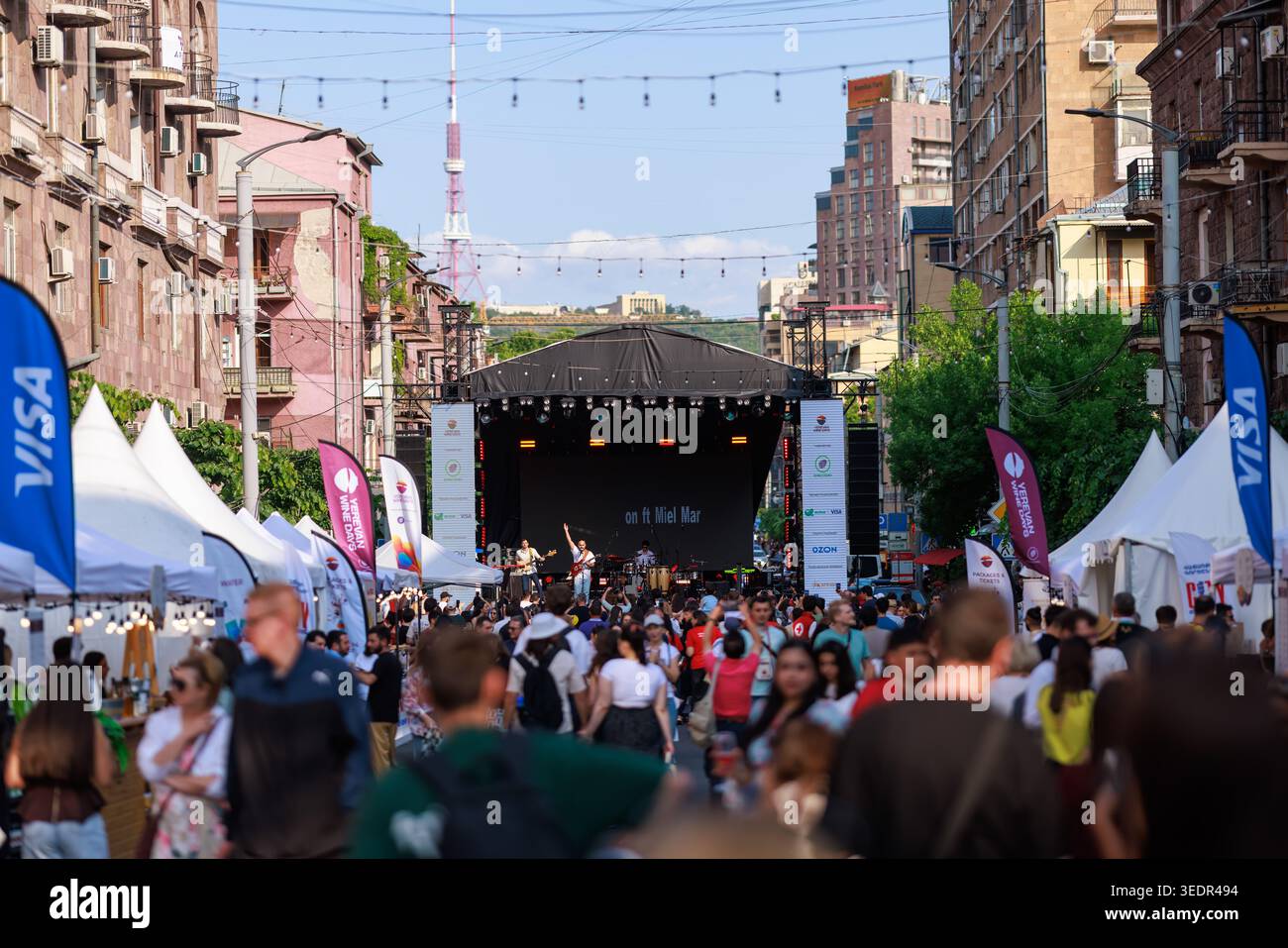 Al Festival del vino di Yerevan i visitatori camminano lungo una strada affollata fiancheggiata da tende di degustazione e un palco principale il 7 giugno 2025 a Yerevan. Foto Stock