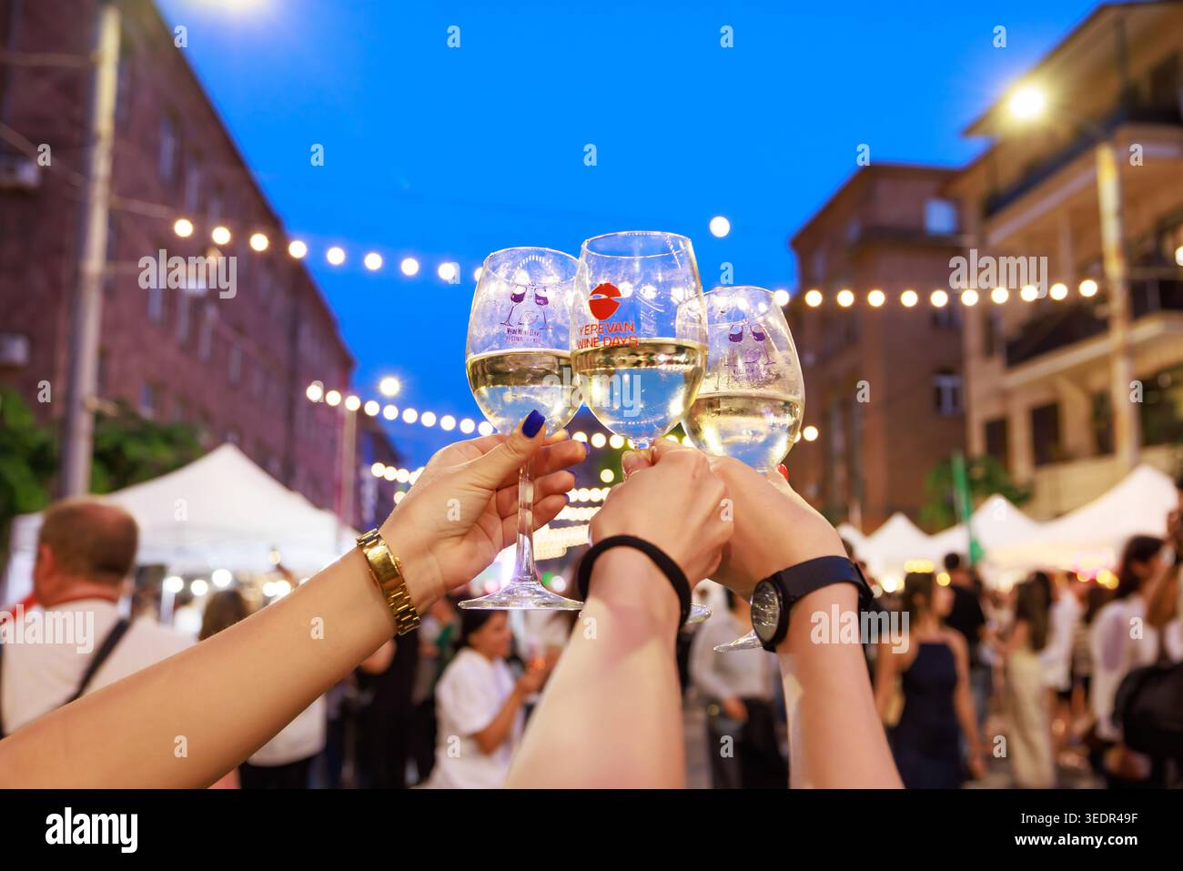 Al Festival del vino di Yerevan, i visitatori alzano tre bicchieri di vino bianco in un brindisi in una strada della città il 7 giugno 2024, a Yerevan, in Armenia. Foto Stock