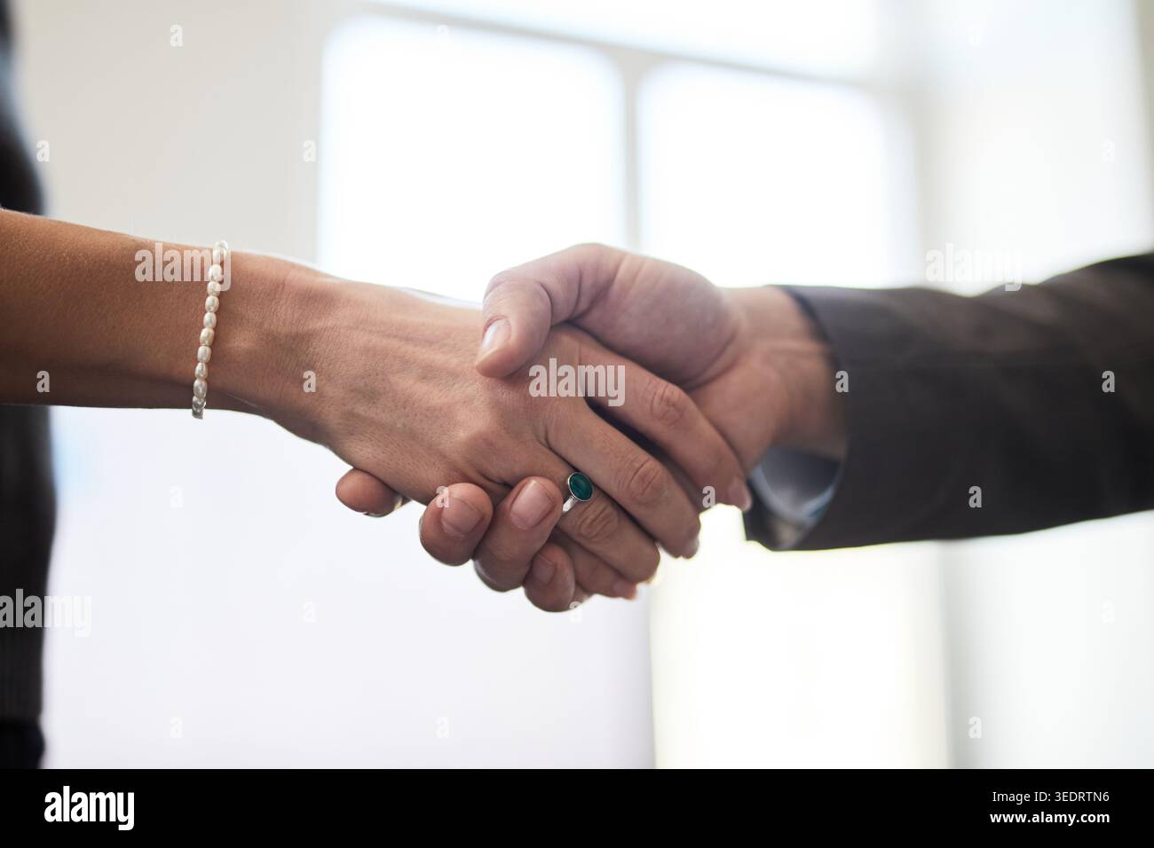 Primo piano di una donna d'affari e di un uomo d'affari che stringono la mano, segnalano partnership, accordo, negoziazione, fiducia nel posto di lavoro. Ideale per comunicazioni aziendali, assunzioni e trattative Foto Stock