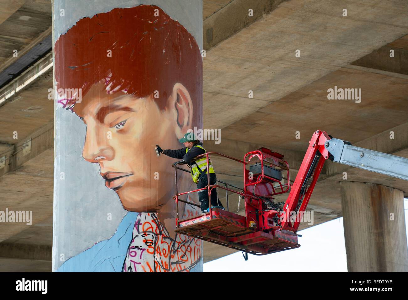 L'artista Freddie, alias Frodrik, dipinge un murale su una grande colonna che sostiene il progetto d'arte del Kingston Bridge per Bridging the Gap Foto Stock