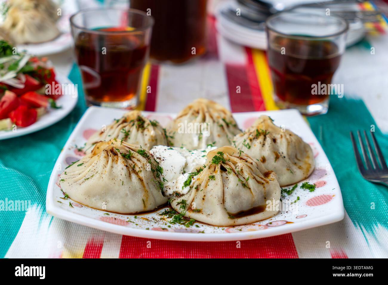 Piatto con mante sul tavolo. Impasto ripieno di carne al vapore. Condito con pepe nero ed erbe aromatiche. Cucina dell'Asia centrale. vista dall'alto Foto Stock