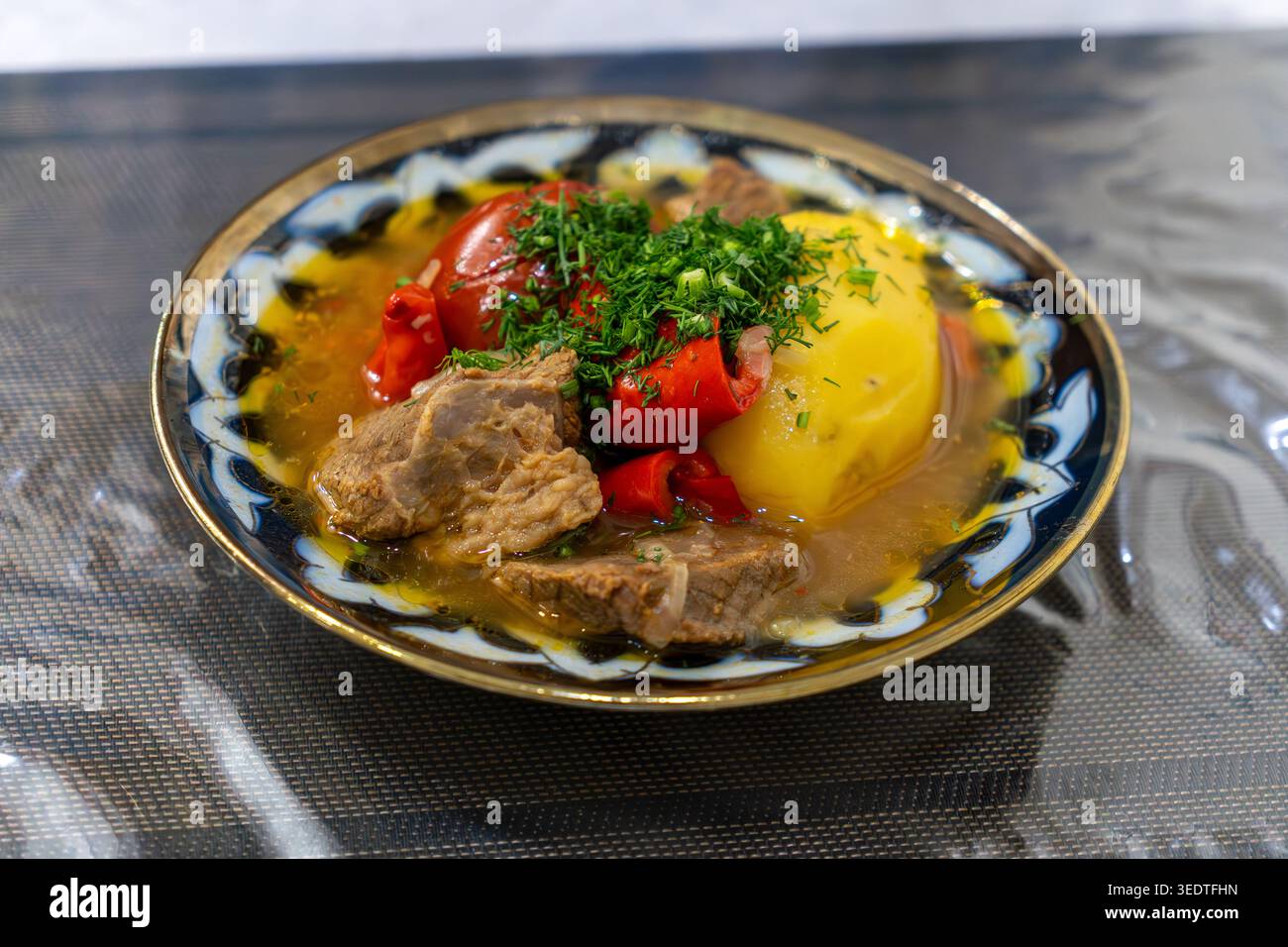 Cibo orientale - zuppa di shourpa con verdure e carne di agnello su un tavolo di legno. Zuppa uzbeka tradizionale con carne di agnello, pepe dolce, pomodori rustici Foto Stock