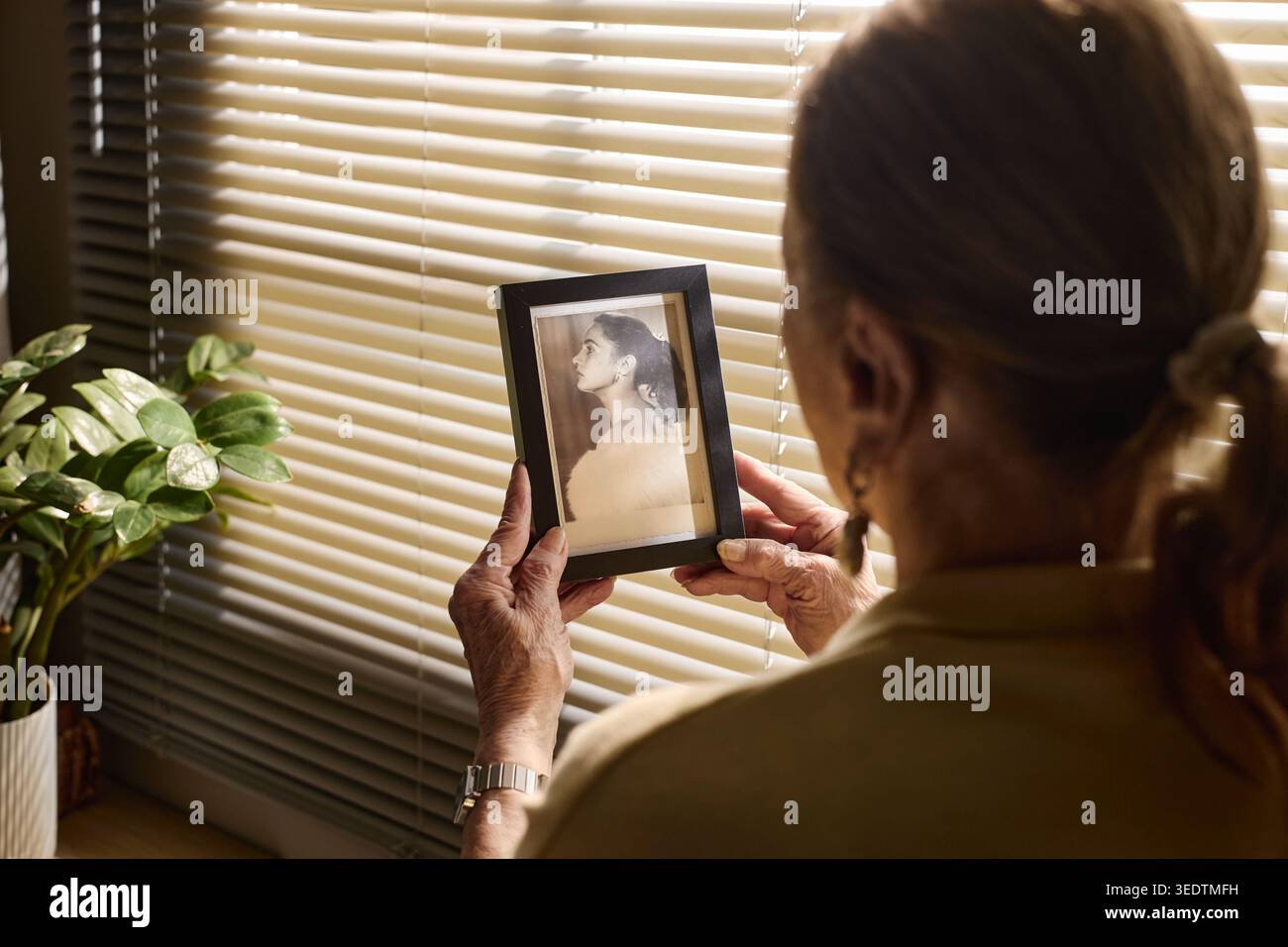 Donna anziana che tiene la foto incorniciata mentre riflette sulla memoria Foto Stock