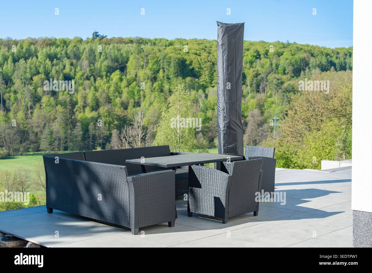 Elegante terrazza esterna con arredi moderni che si affaccia su un paesaggio naturale. Il design pulito crea uno spazio rilassante e confortevole per il tempo libero Foto Stock