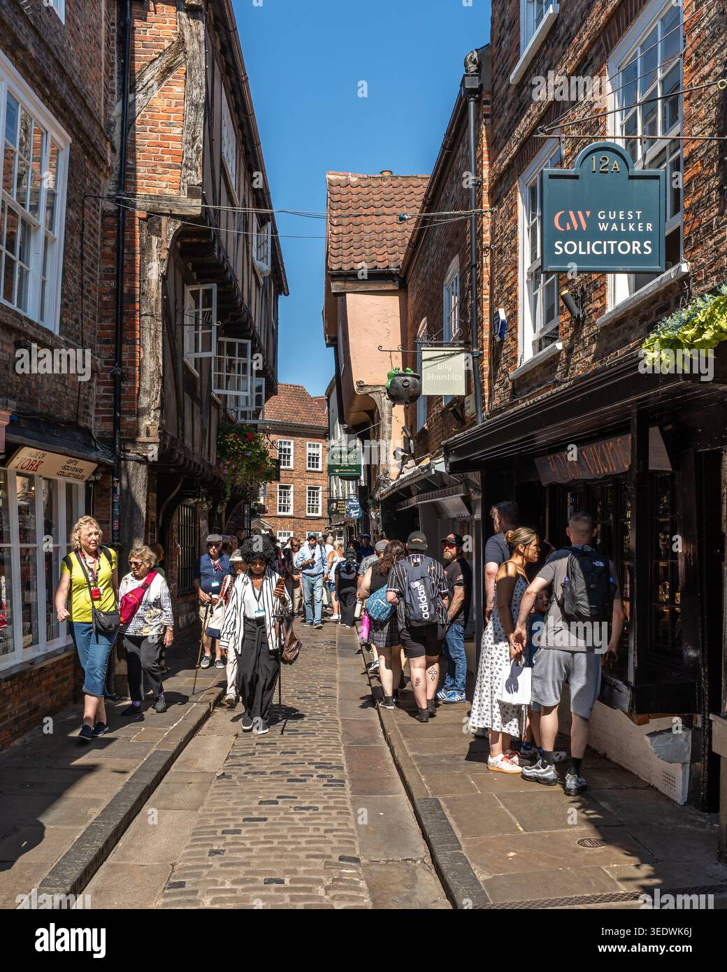 I turisti camminano attraverso The Shambles, una famosa strada medievale con travi in legno che presenta le storiche vetrine di York, Inghilterra Foto Stock