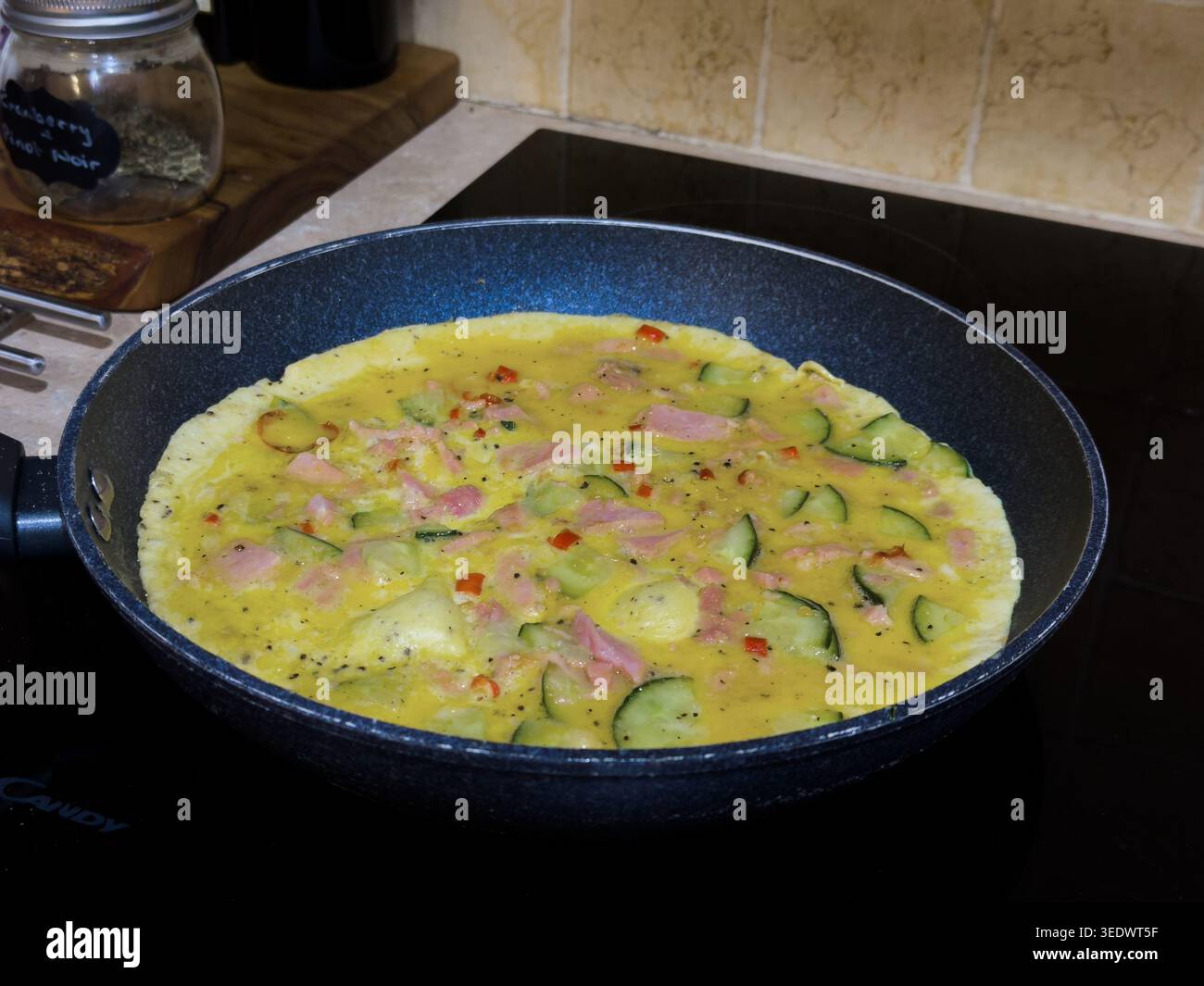 Un'omelette in una padella che viene cucinata Foto Stock