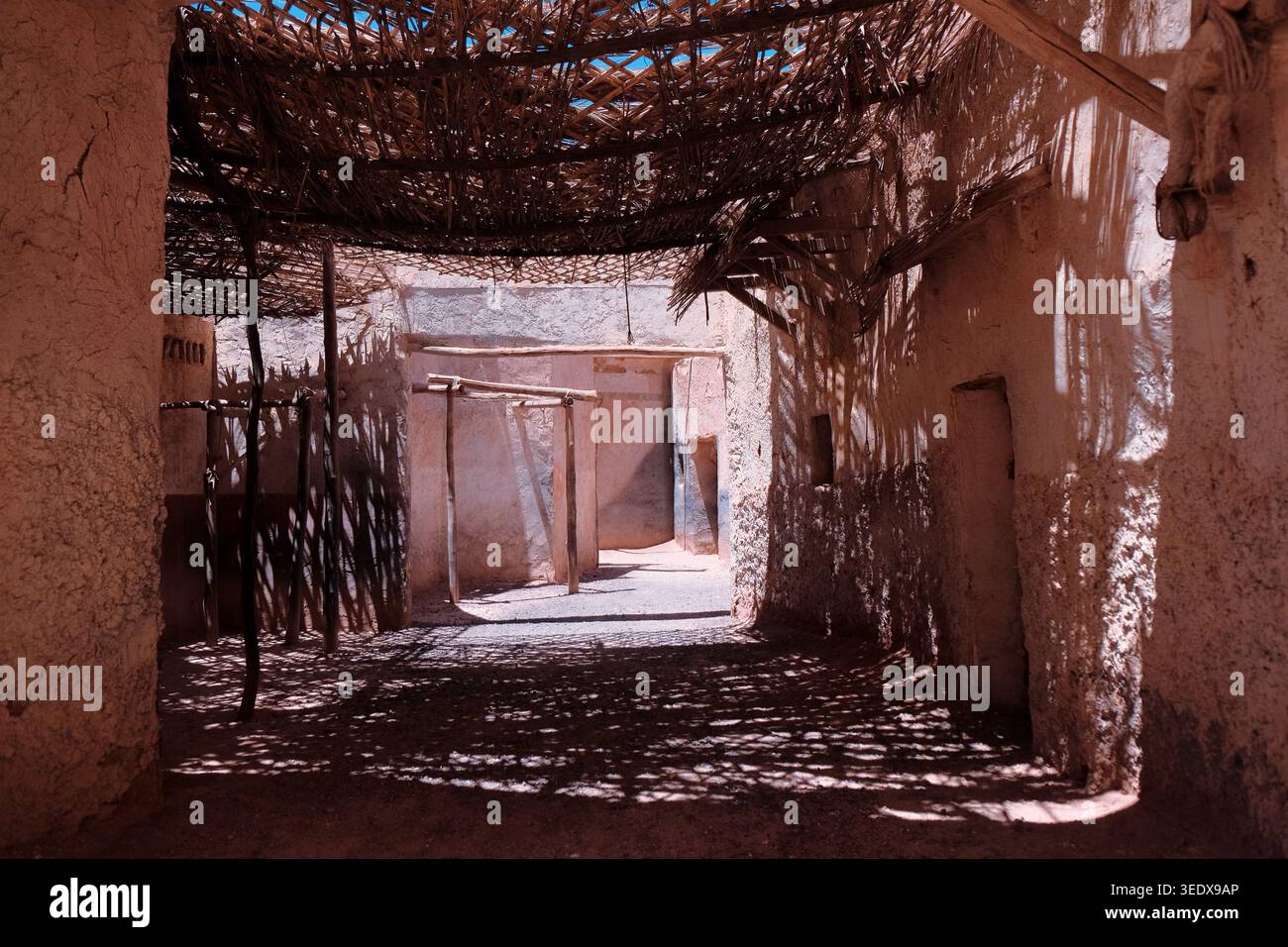Ouarzazate, Marocco: Interno del film ambientato nel deserto presso gli Atlas Film Studios con ombre del tetto di canne su pareti di argilla rossa. Sfondo di viaggio. Estate esotica. Foto Stock