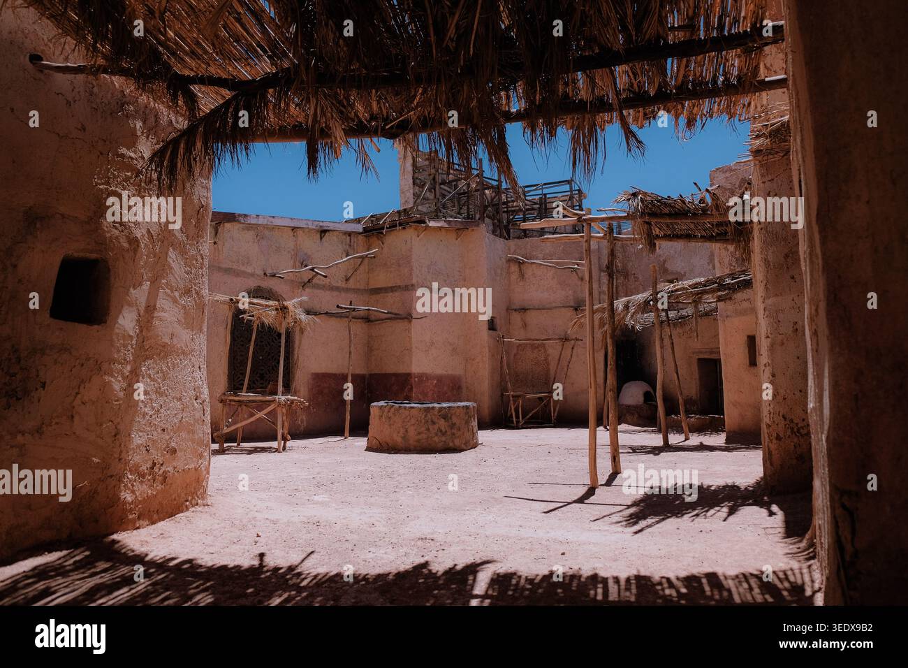 Ouarzazate, Marocco: Antico villaggio con pozzo di pietra e impalcature in legno agli Atlas Film Studios sotto il cielo blu. Sfondo dei viaggi estivi. Foto Stock