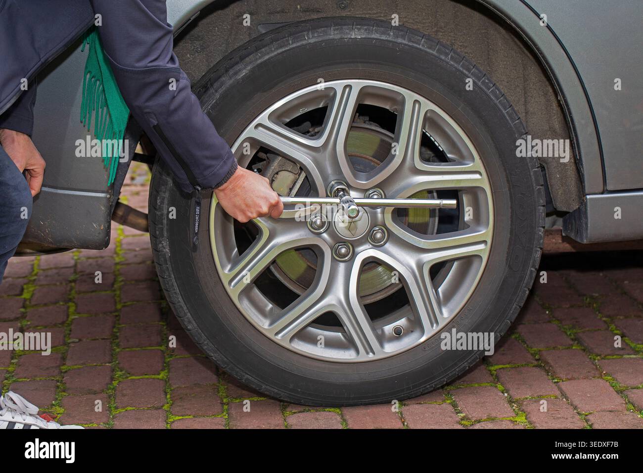 Per sostituire uno pneumatico di un'auto, è necessario allentare le viti sulla ruota per rimuovere lo pneumatico. La posizione in cui viene mantenuta la chiave determina la leva Foto Stock