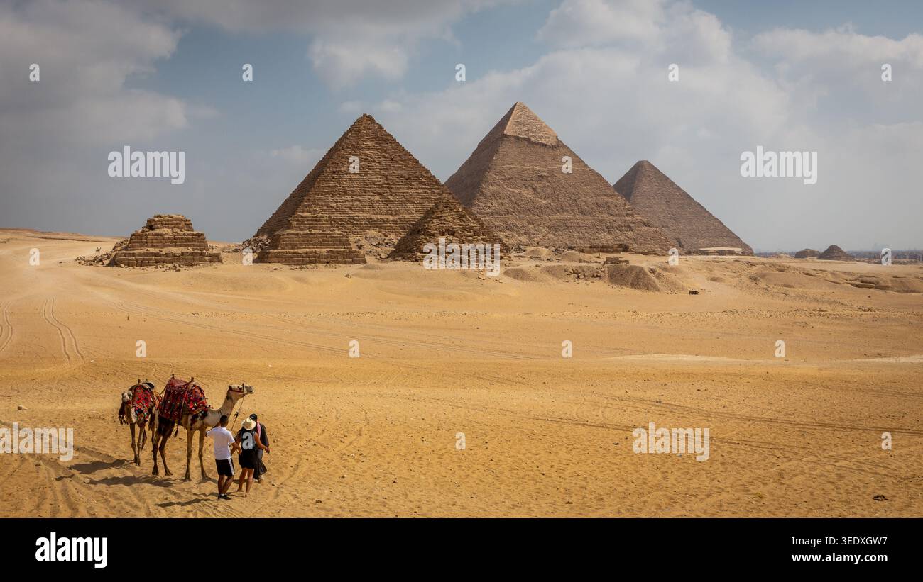 Complesso delle piramidi di Giza in Egitto, vista dal deserto con un giro in cammello intorno alle piramidi. Foto Stock