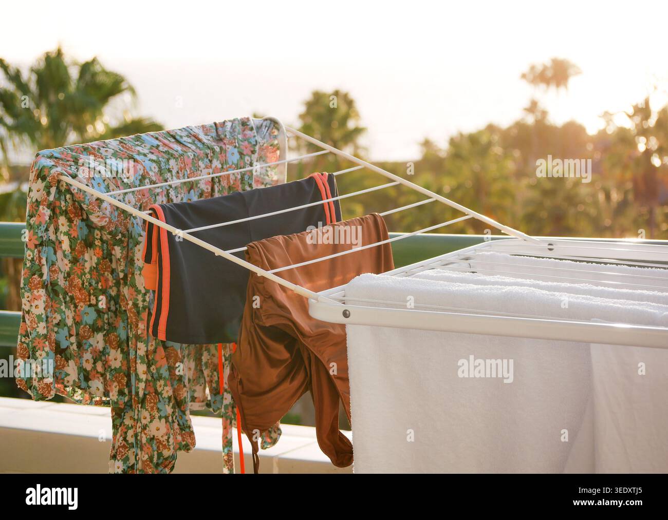 Lavanderia e abbigliamento da spiaggia asciugati su un portabagagli al tramonto. Confortevole scenario di viaggio con sfondo tropicale, luce del sole, atmosfera da vacanza ed eco-frien Foto Stock