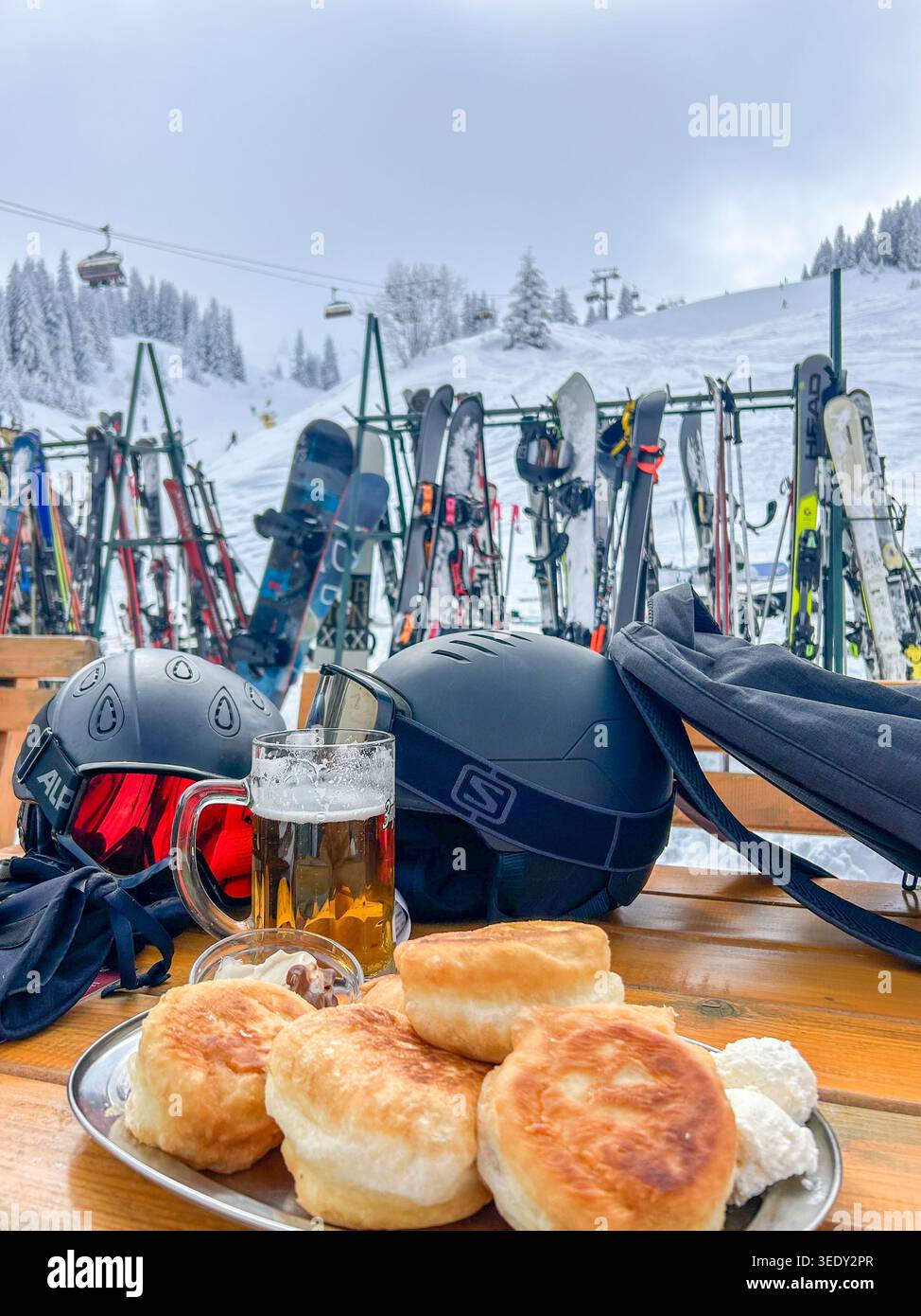 Caschi da sci, snowboard e uno spuntino invernale con pasticcini e birra sulla terrazza après-ski del monte Jahorina. - Immagine stock catturata con smartphone
