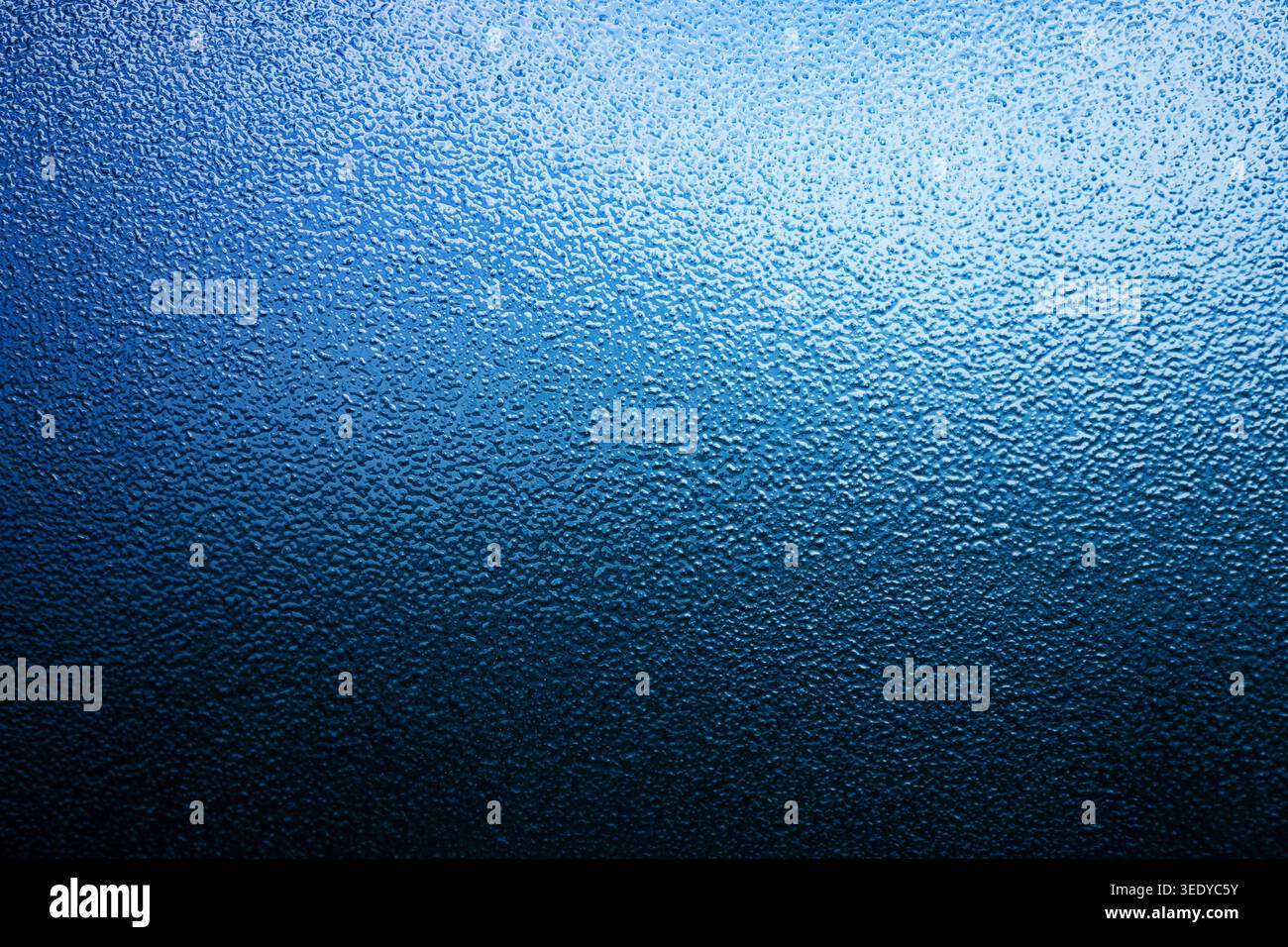La consistenza del vetro ruvido blu brillante si dissolve in un'ombra profonda sul fondo Foto Stock