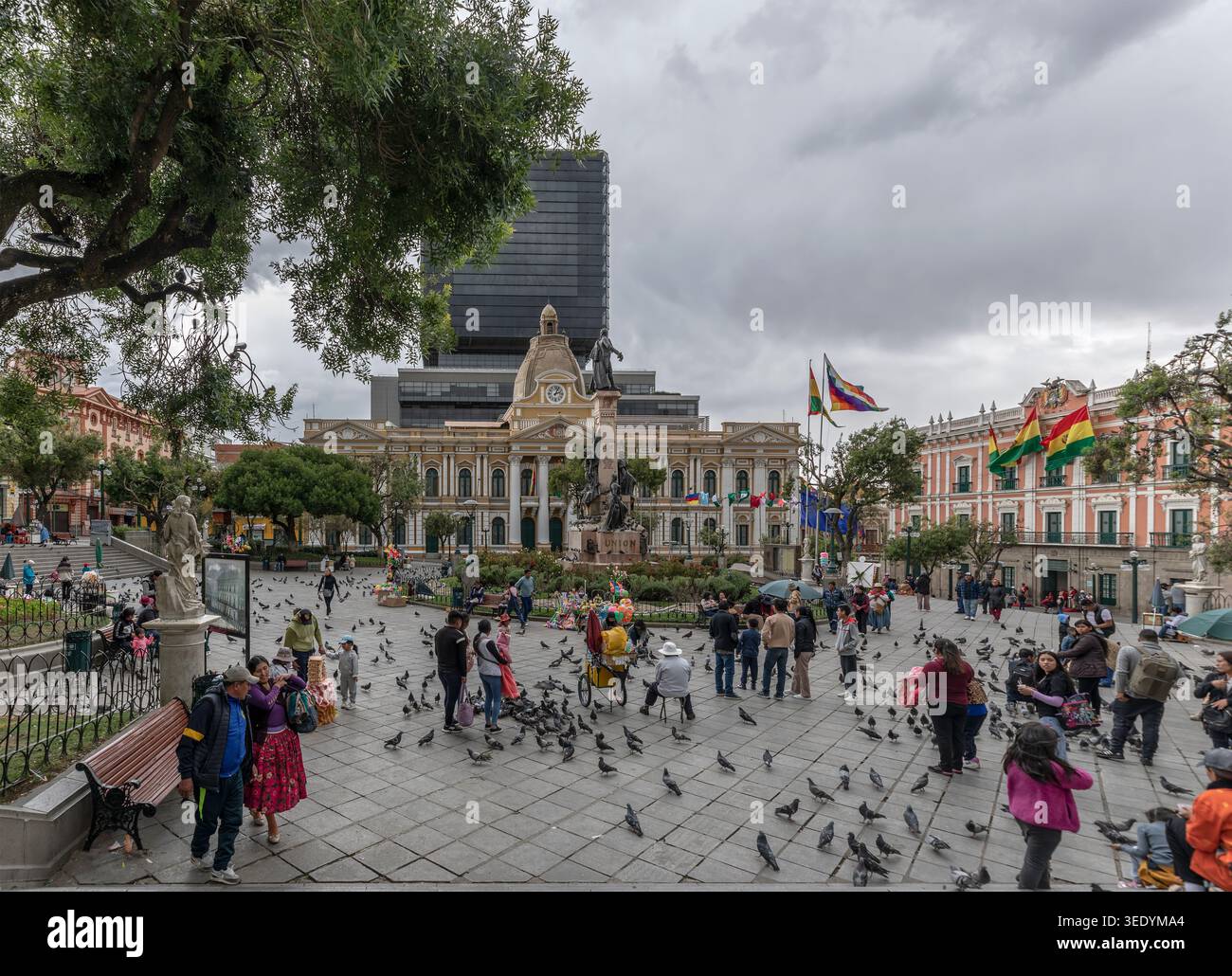 Turisti alimentano piccioni nella Plaza Murillo, La Paz, Bolivia, vicino alla statua di Murillo, al Palacio Quemado e all'edificio dell'Assemblea legislativa plurinazionale Foto Stock