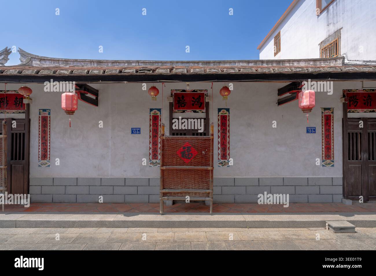 Residenza tradizionale con pareti bianche con Couplet e Lanterne rosse sulla via antica di Linjiang, la città antica di Yuegang, Zhangzhou, Fujian, Cina Foto Stock