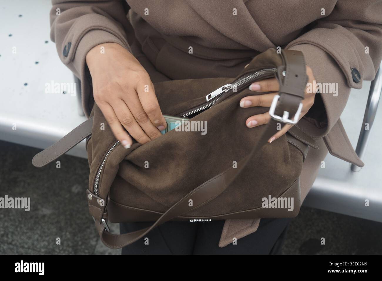 Donna controlla la borsa alla fermata dell'autobus nell'area urbana Foto Stock