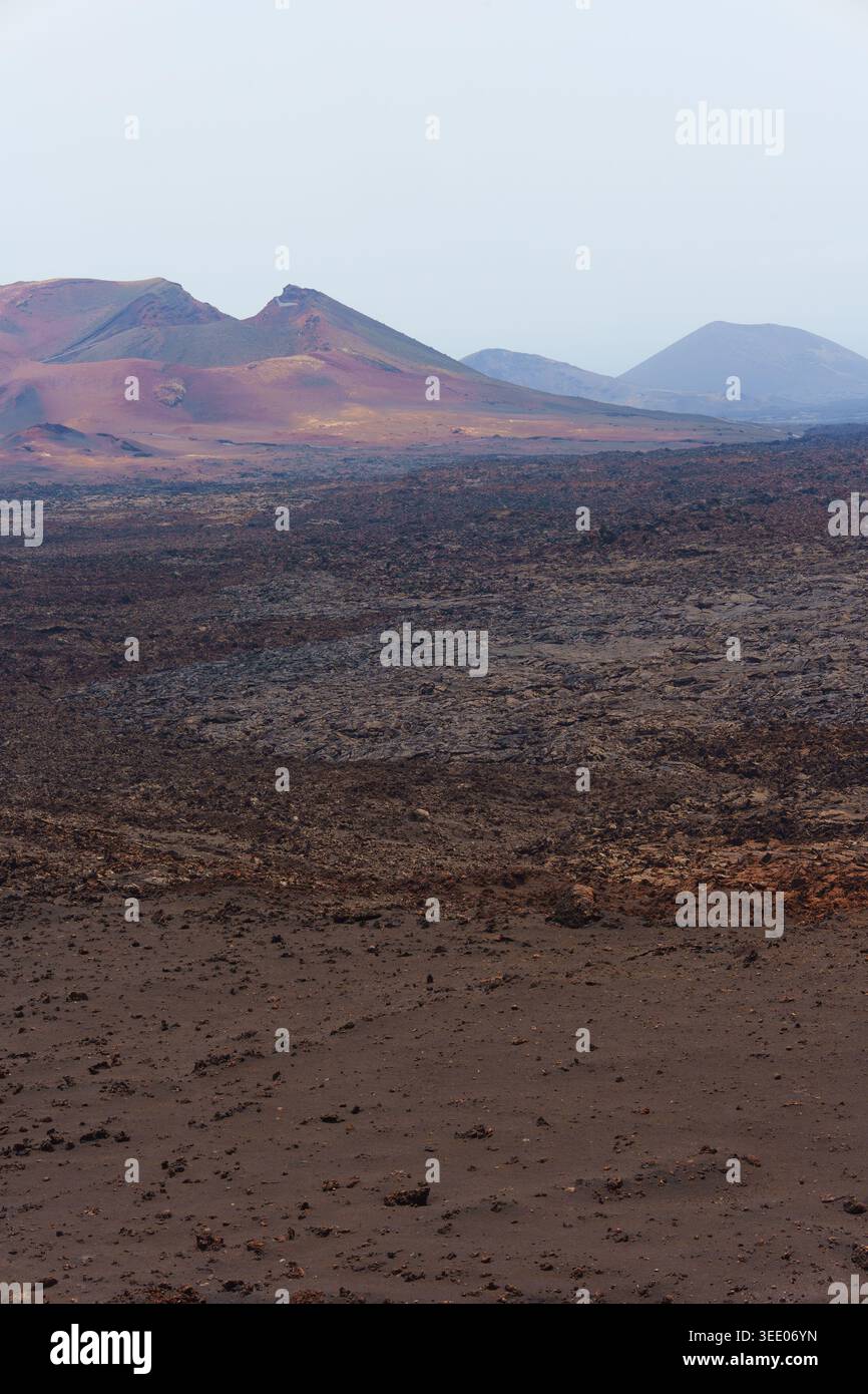 Montagne vulcaniche che si innalzano su un vasto campo di lava e terra scura Foto Stock