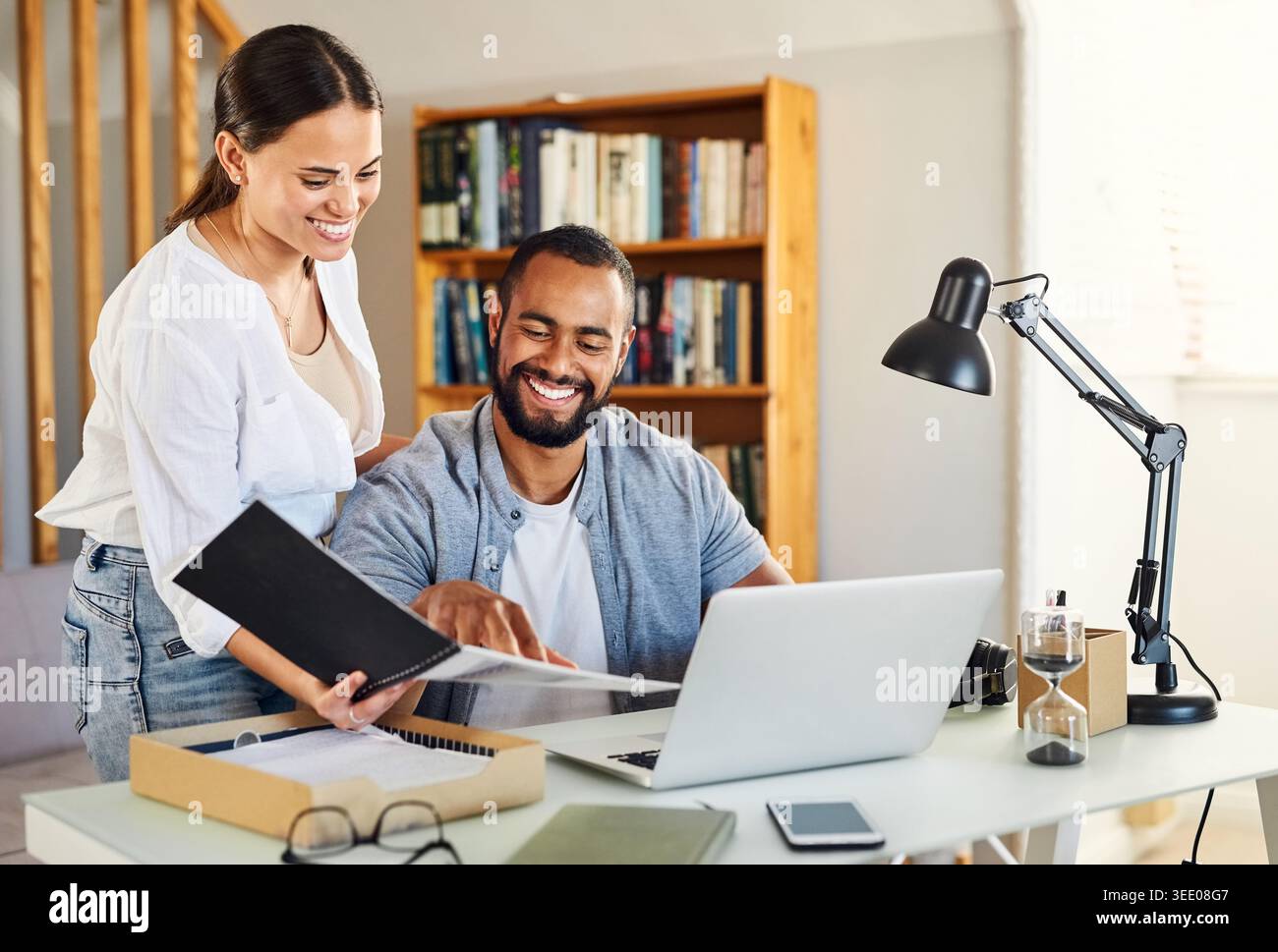 Documenti, laptop e lavoro in remoto con una coppia nello studio domestico per la pianificazione di piccole imprese. Computer, cartelle e sorrisi con il personale freelance alla scrivania Foto Stock