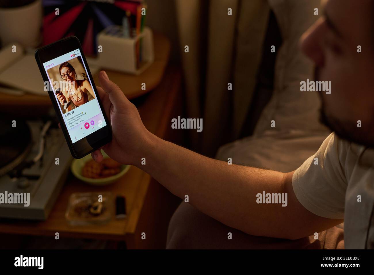 Giovane uomo adulto che tiene in mano lo smartphone, sta navigando sul profilo dell'app di incontri mentre è seduto a casa. Concept che mostra matchmaking online, romanticismo mobile, digital relationship marketing Foto Stock