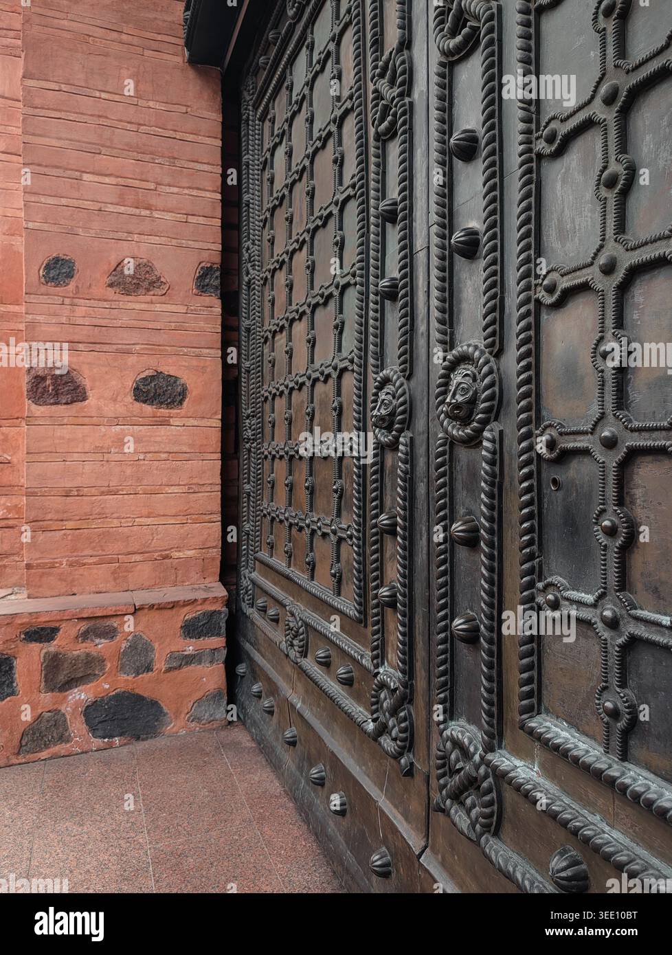 Lavori in metallo ornato sul Golden Gate di Kiev. Una prospettiva dettagliata delle intricate porte placcate in bronzo e delle pareti in mattoni testurizzati della storica fortezza. Foto Stock