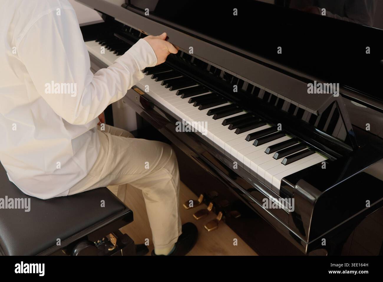 Pianista in abito bianco che suona il Grand piano vista laterale Foto Stock