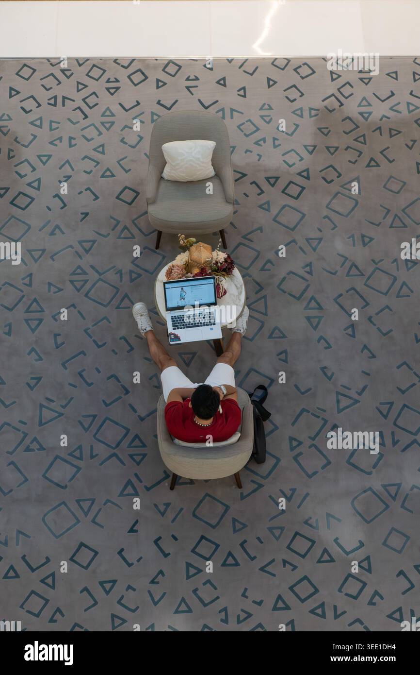 Vista dall'alto dell'uomo che utilizza un computer portatile al Dubai Mall, Emirati Arabi Uniti Foto Stock