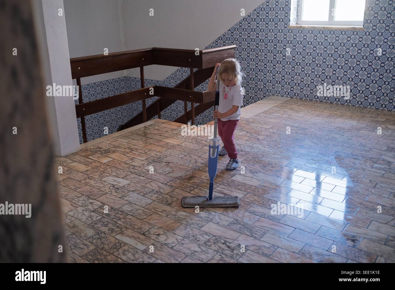 L'industria e la responsabilità nell'infanzia mentre i bambini puliscono i pavimenti interni piastrellati tradizionali Foto Stock