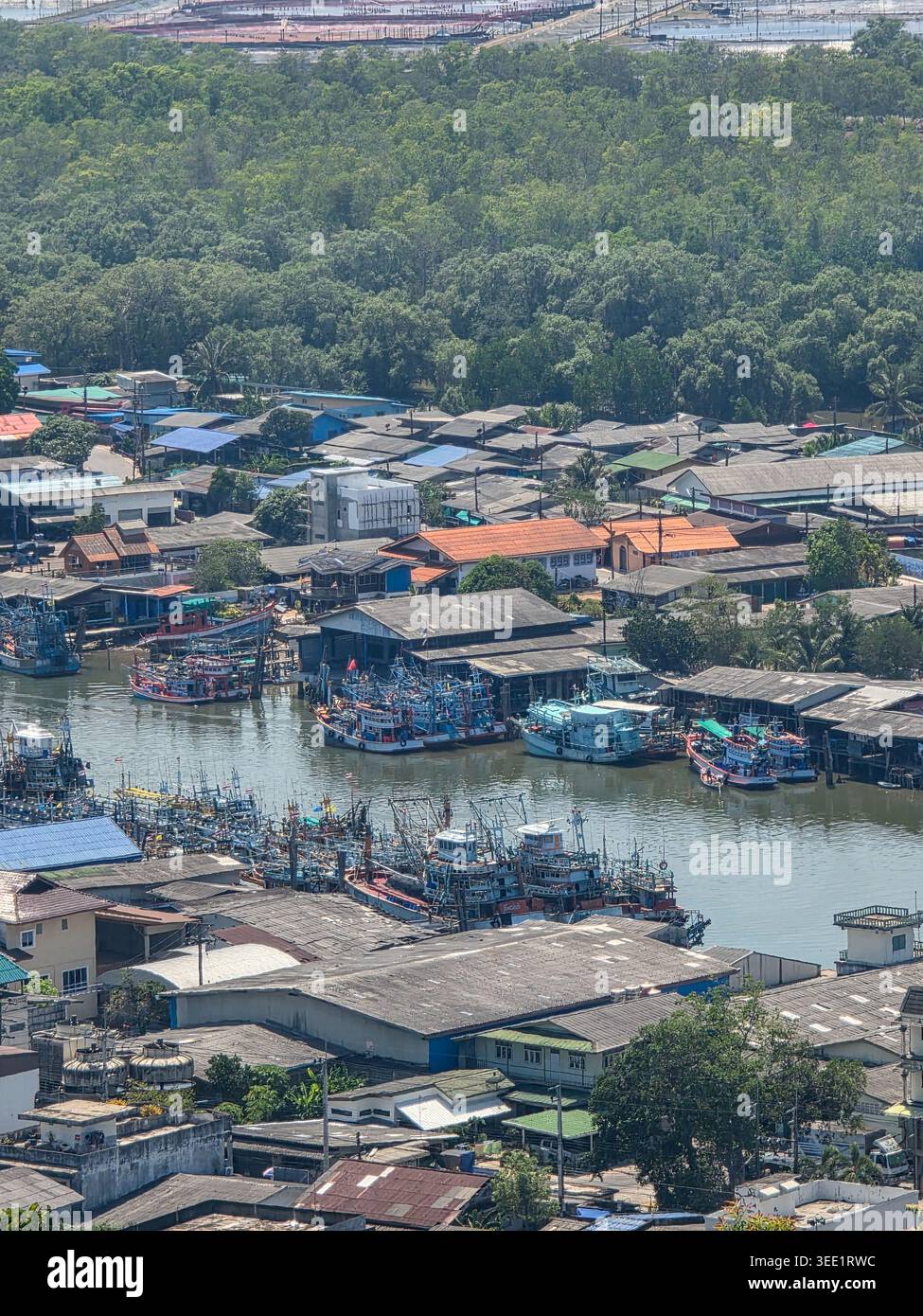 Tranquilla vista aerea che cattura il tradizionale villaggio di pescatori lungo il tranquillo fiume mostrando una piccola barca ormeggiata vicino alla comunità costiera con colorati tetti di latta Foto Stock