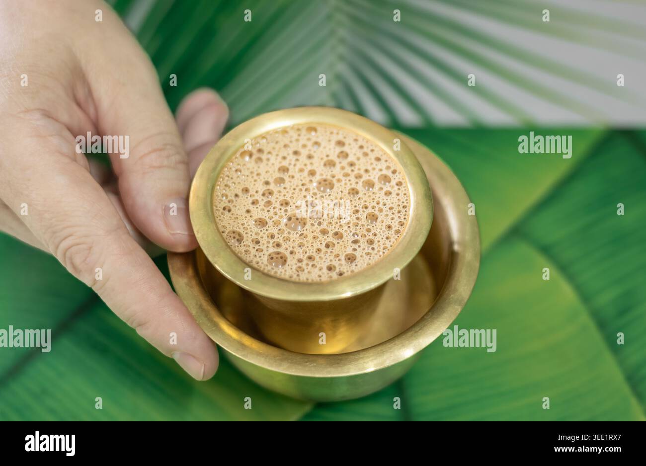 A mano con un chai di tè caldo fresco in una tazza di metallo. Tradizionale tè indiano masala chai per colazione in un bicchiere di vetro da caffè in ottone, vista dall'alto. Nessuno Foto Stock