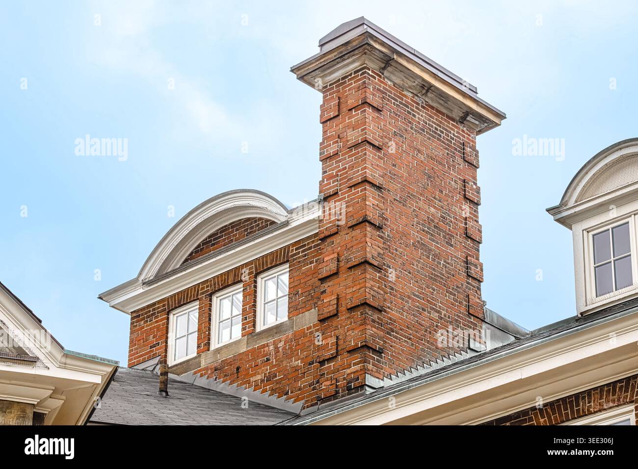 Primo piano del tetto della Flavelle House con camino in mattoni, finestre dormitori e dettagli architettonici classici contro il cielo blu. Foto Stock