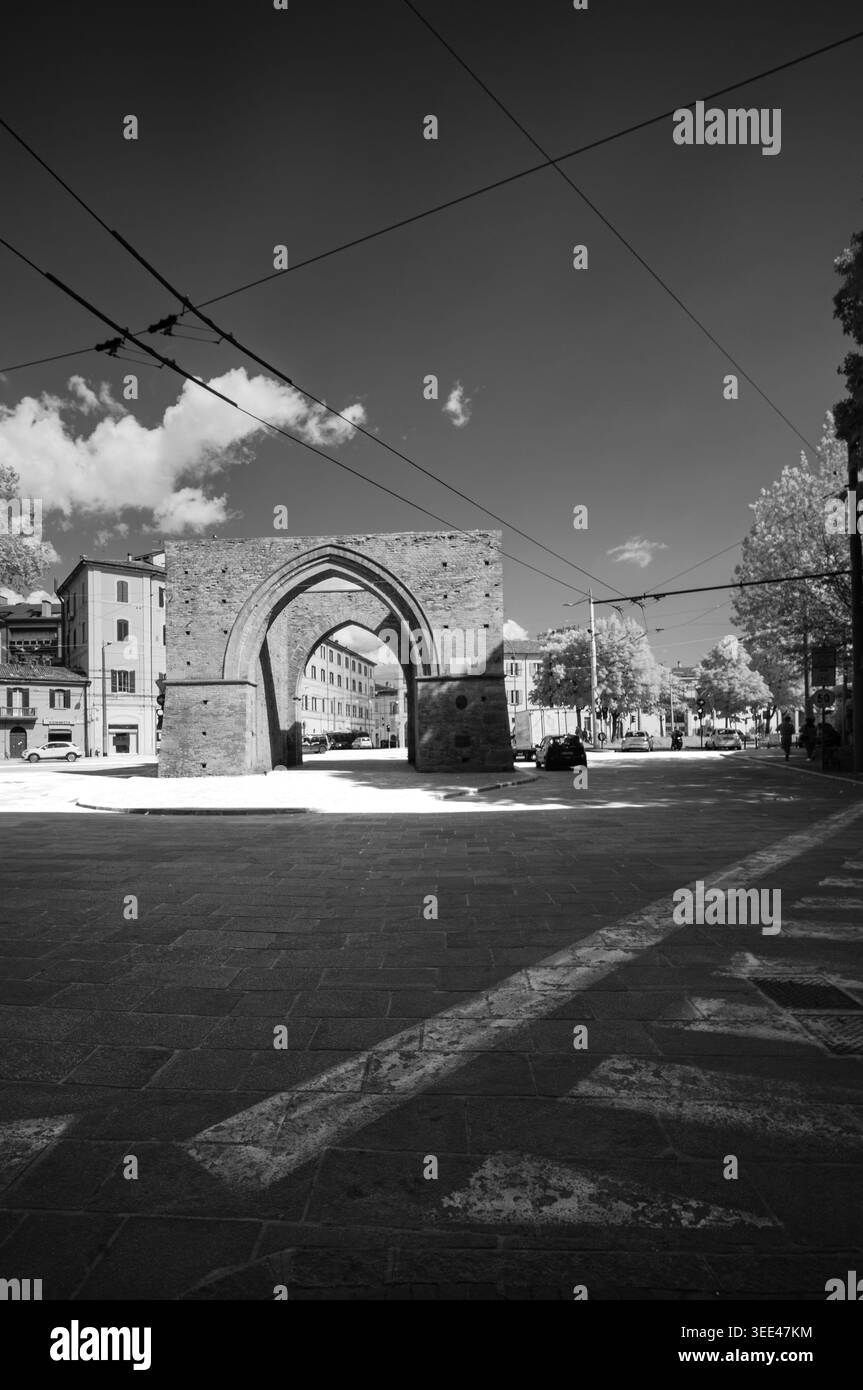 Fotografia in bianco e nero con porta Saragozza a Bologna, Italia. L'antico arco in mattoni incornicia una strada trafficata con edifici, automobili e oltre Foto Stock