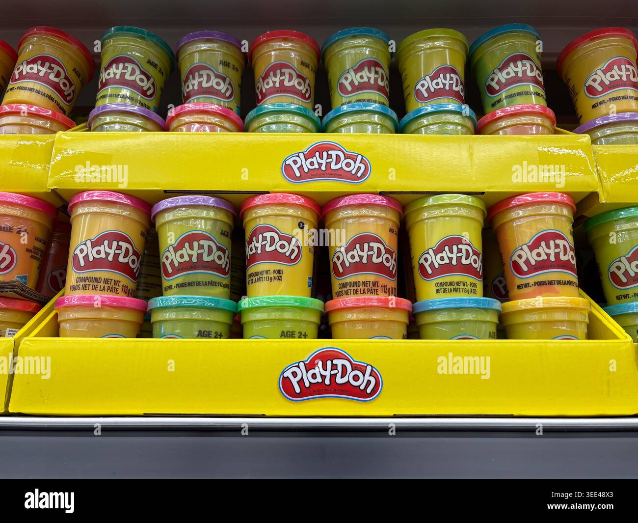 File di colorate lattine composte per modellare Play-Doh esposte in un vassoio di cartone giallo con marchio in un negozio di giocattoli. Foto Stock