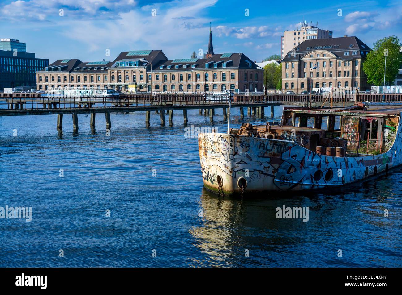 L'ex nave MS Dr. Ingrid Wengler ha ricoperto di graffiti sul fiume Sprea a Berlino, in Germania, con moderni edifici Mediaspree sullo sfondo. Foto Stock