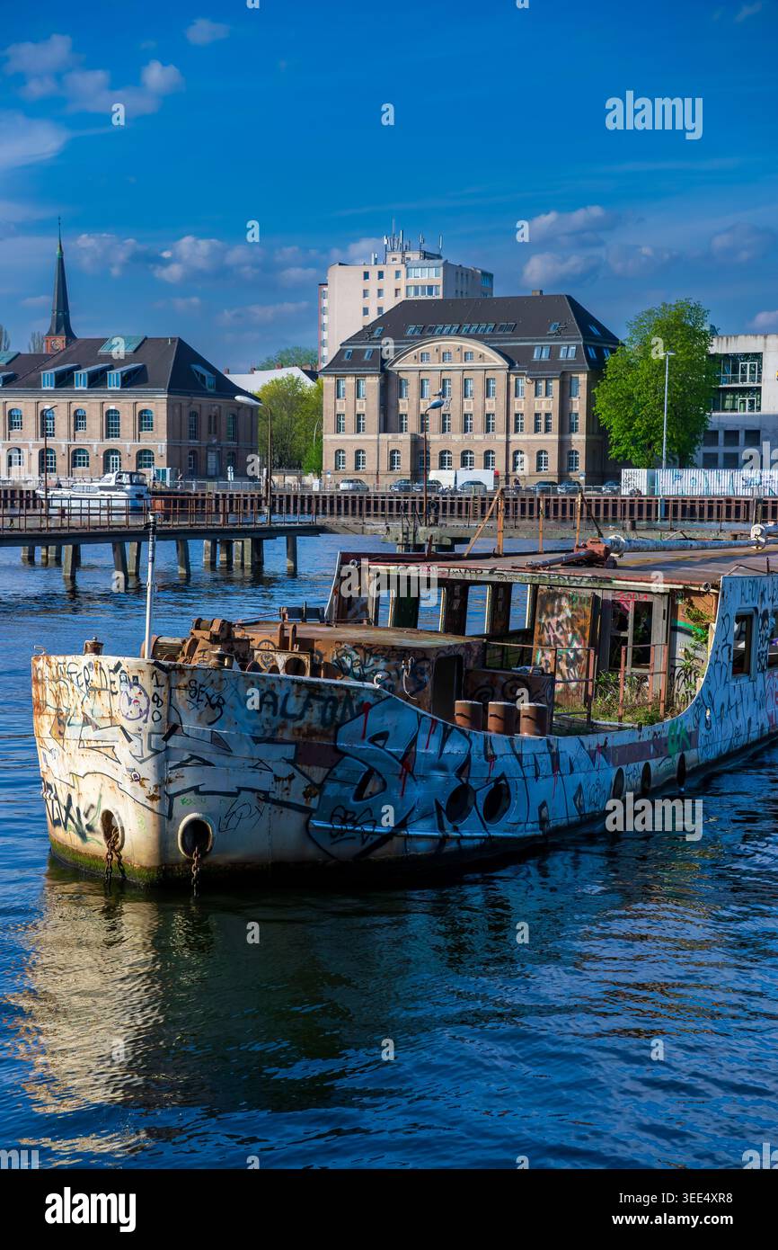 L'ex nave MS Dr. Ingrid Wengler ha ricoperto di graffiti sul fiume Sprea a Berlino, in Germania, con moderni edifici Mediaspree sullo sfondo. Foto Stock