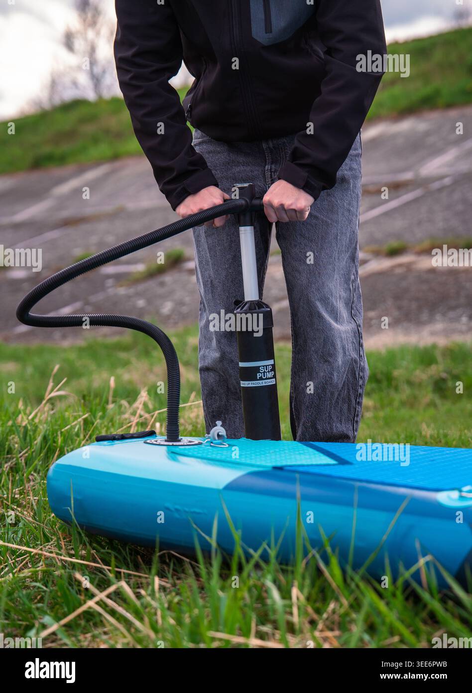 Uomo che gonfia il pannello blu gonfiabile Stand Up Paddle con una pompa manuale Foto Stock
