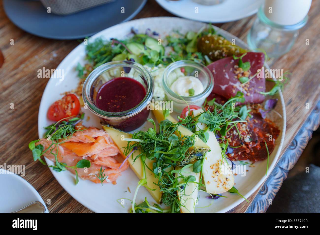 Colazione o brunch a base di salmone affumicato, formaggi artigianali, affettati, microgreen freschi e salse gourmet servite in un ambiente da caffetteria tedesca Foto Stock