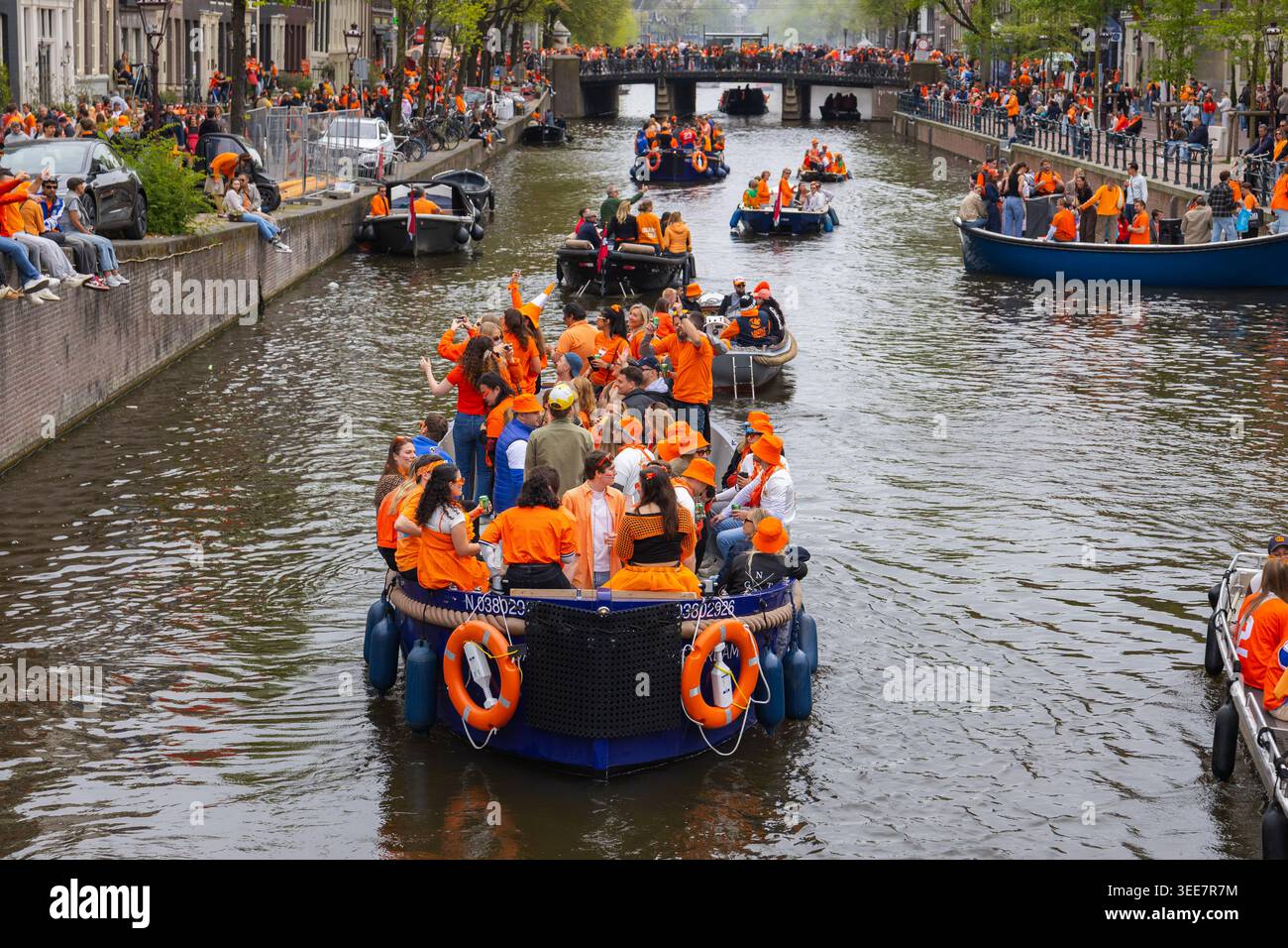 Amsterdam, Paesi Bassi - 27 aprile 2026: La folla si gode il Kings Day sui canali di Amsterdam indossando l'arancio e festeggiando con le barche e. Foto Stock