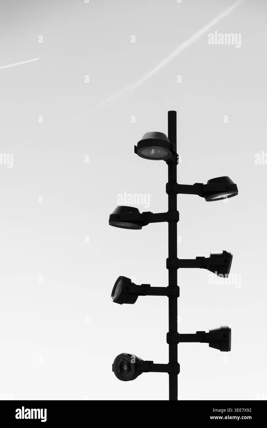 Silhouette minimalista in bianco e nero di un lampione a più frontali contro un cielo limpido Foto Stock