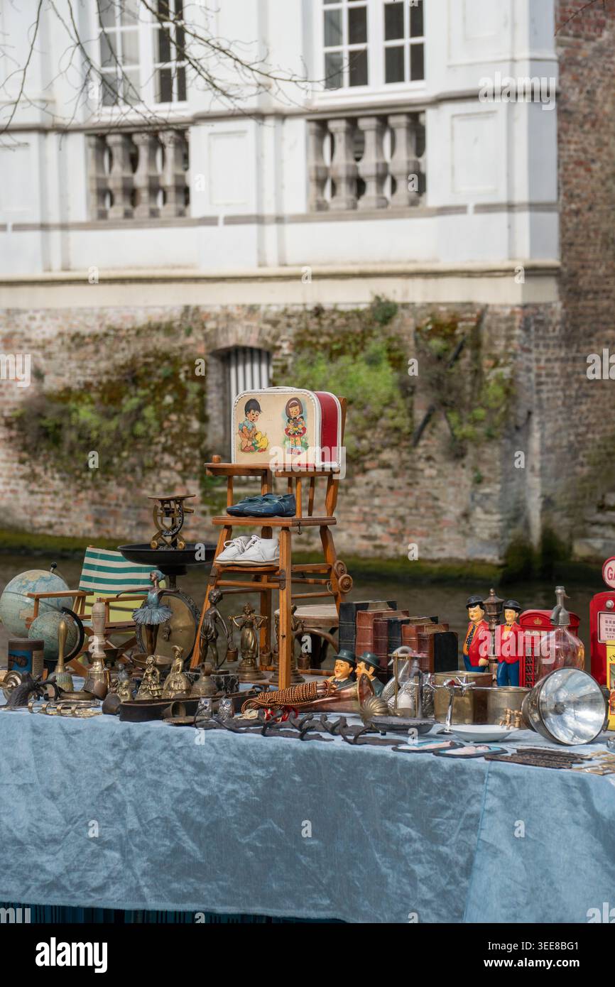 Bruges, Belgio - 4 aprile 2026: Esposizione all'aperto di oggetti d'antiquariato, oggetti metallici, piccole statuette, scatola d'epoca, vetreria, oggetti da collezione nelle vicinanze Foto Stock