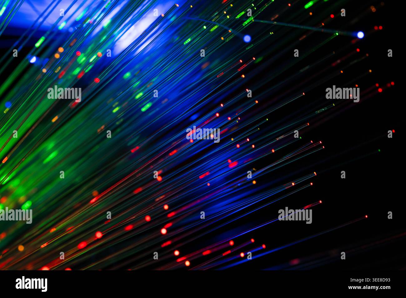 Immagine astratta dinamica con tracce di luce in fibra ottica blu, verde e rossa con particelle luminose su sfondo scuro. Concetto di inter. Ad alta velocità Foto Stock