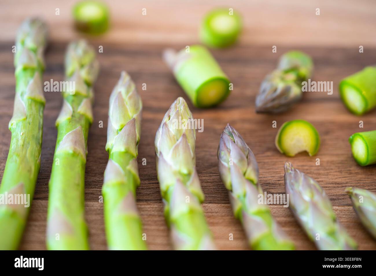 Asparagi commestibili (Asparagus officinalis) o asparagi da giardino tritati su un tagliere in legno di noce, Regno Unito. Concetto: Cucina, cinque al giorno, cibo ricco di ferro Foto Stock