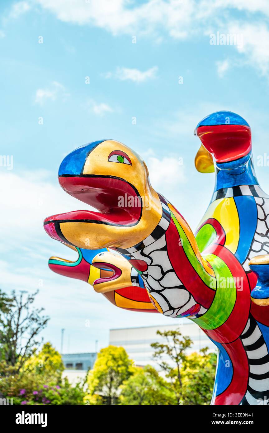Colorata scultura astratta all'aperto a Tokyo caratterizzata da forme multicolori intrecciate, adagiate tra il verde in uno spazio pubblico. Foto Stock
