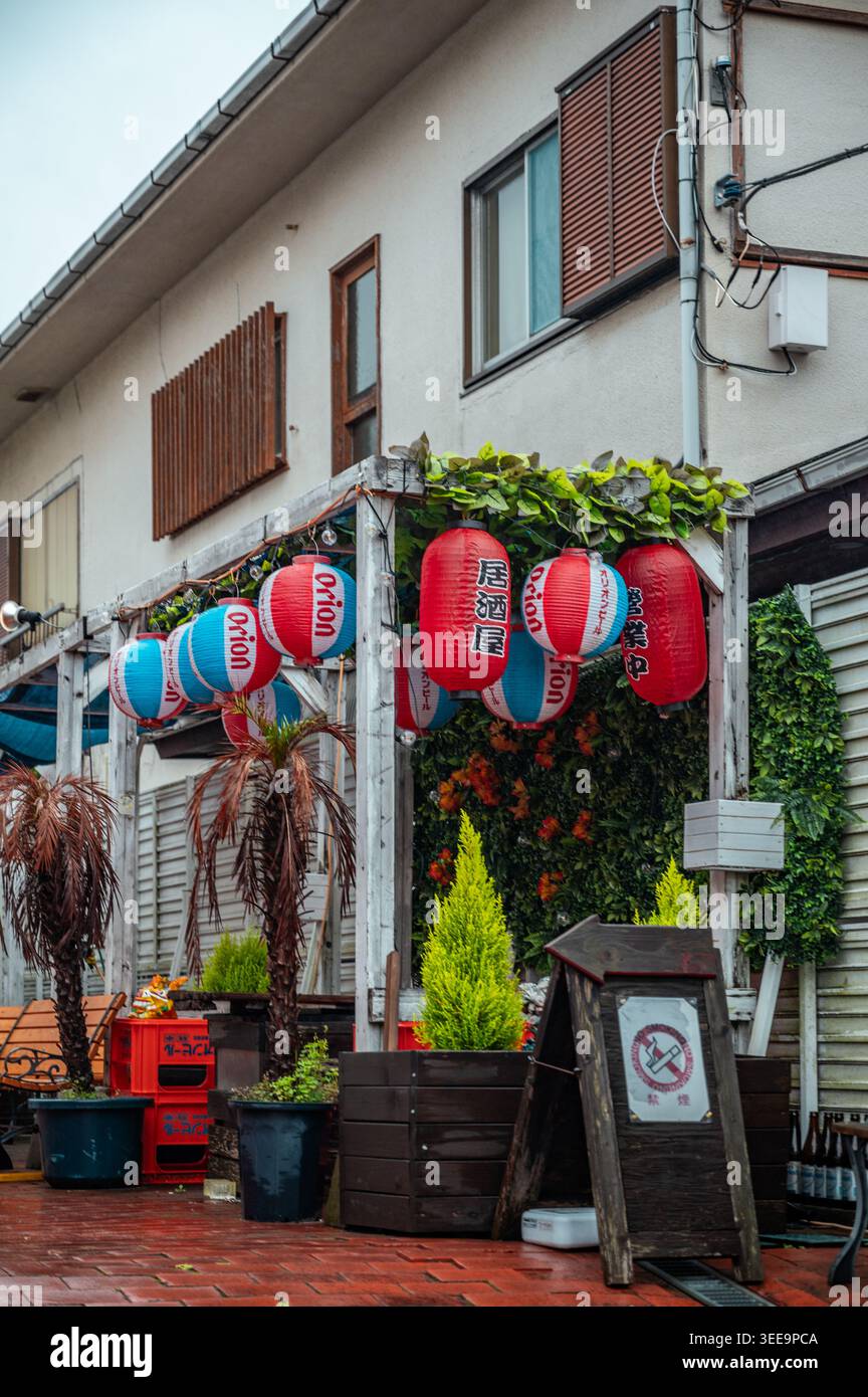 Lanterne giapponesi rosse e blu appese all'esterno del ristorante con piante e area salotto a Kamakura, Kanagawa, Giappone Foto Stock
