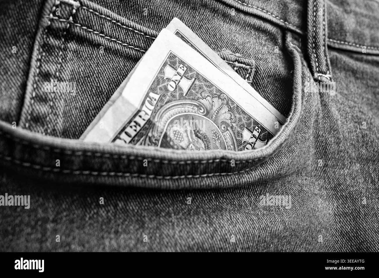 Banconota da un dollaro sbirciato da una tasca di jeans che rappresenta denaro in tasca, budget, finanze personali, risparmi, flusso di cassa e abitudini di spesa quotidiane. Foto Stock