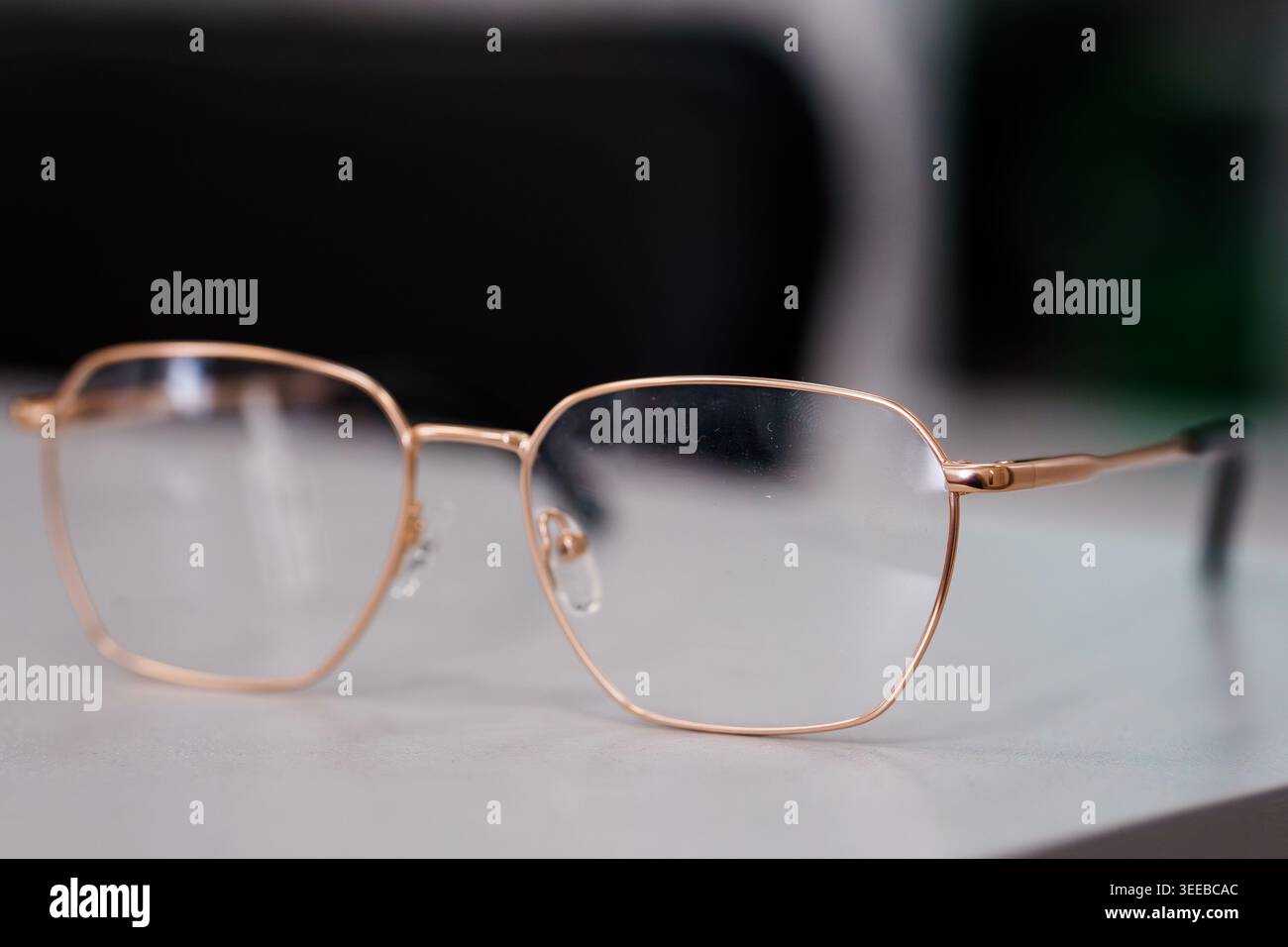 Occhiali moderni con montatura in metallo su una scrivania pulita che rappresenta l'optometria, la cura della vista e l'estetica contemporanea del design degli occhiali Foto Stock